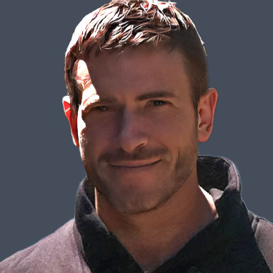 Headshot of salon owner Ricky Hobbs smiling staring at the camera wearing a collared pullover