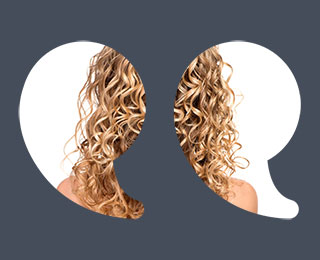 Back view of woman facing away with long curly hair with blonde highlights